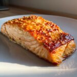 Close-up of a moist, flaky air fryer salmon fillet with a shiny, caramelized glaze topping.
