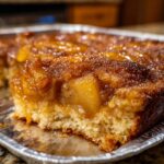 A close-up view of a moist slice of caramel apple dump cake with a rich, gooey caramel topping.