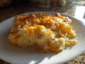 A close-up serving of cheesy chicken and rice casserole with a golden, melted cheese topping.