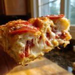 Close-up of a cheesy, gooey pizza sliders piece being pulled apart, showing melted mozzarella and pepperoni.