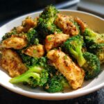 Close-up of golden-brown seasoned chicken pieces mixed with bright green broccoli florets in a white bowl.