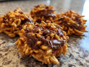 Four no-bake haystack cookies made with chow mein noodles and topped with melted chocolate drizzle.