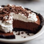 Close-up of a rich slice of Christmas chocolate cream pie showing the dark crust, thick filling, and whipped cream topped with chocolate shavings.