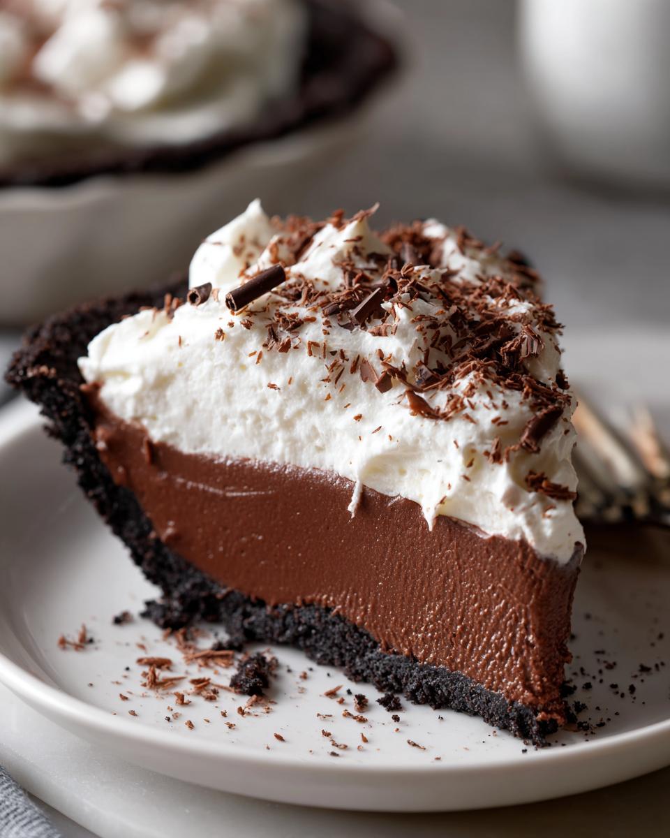 A perfect slice of Christmas chocolate cream pie featuring a dark crust, rich chocolate filling, and whipped cream topped with chocolate shavings.