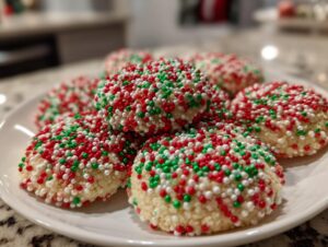 A close-up of soft, round christmas sprinkle sugar cookies covered entirely in red, green, and white nonpareils.