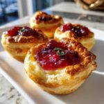 Close-up of warm cranberry brie bites made with flaky pastry, melted brie, and cranberry topping.