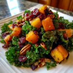 Close-up of a vibrant Fall Harvest Salad featuring kale, roasted butternut squash cubes, pecans, and dried cranberries.