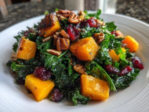 Close-up of a vibrant Fall Harvest Salad featuring dark green kale, roasted orange butternut squash cubes, pecans, and dried cranberries.