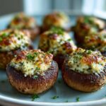 Close-up of baked stuffed mushrooms with a cheesy, herbed filling, garnished with fresh parsley.