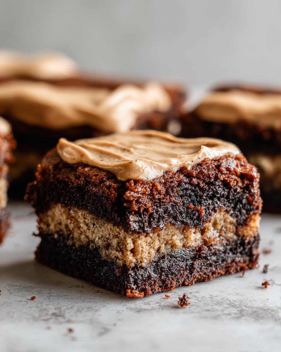 Close-up of a layered banana bread brownies square with a thick peanut butter frosting topping.