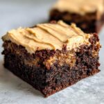 Close-up of a moist banana bread brownies square topped with creamy peanut butter frosting.