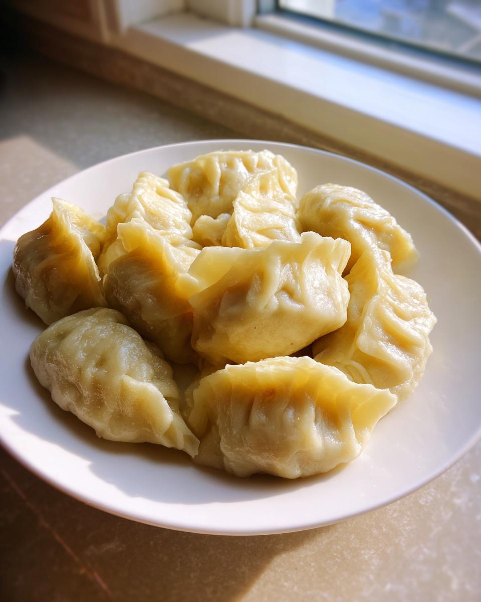 A plate filled with freshly steamed Traditional Chinese Dumplings, lit by natural sunlight near a window.
