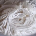 Close-up of thick, glossy, white royal icing recipe mixture showing stiff peaks and swirling texture.