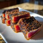 Slices of perfectly Seared Ahi Tuna with a dark, crunchy sesame and pepper crust, showing a rare red center.
