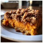 Close-up of a square slice of bright orange southern sweet potato casserole topped with a crunchy pecan streusel.