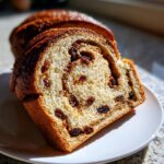 Close-up of a thick slice of homemade raisin bread showing the soft interior and cinnamon swirl.