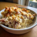 Close-up of a serving of hot, cheesy Reuben dip topped with melted, browned cheese and herbs in a small white ramekin.