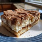 A thick, creamy slice of churro cheesecake topped generously with cinnamon sugar mixture.