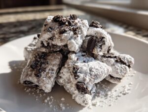Close-up of a pile of homemade cookies and cream puppy chow coated heavily in powdered sugar.