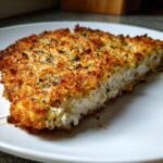 Close-up of a perfectly golden brown, breaded slice of caesar chicken showing the white interior.