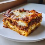 A perfect square slice of sheet pan lasagna with rich meat sauce and browned cheese topping.