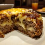 Close-up of a slice of crockpot french onion meatloaf showing melted cheese oozing out of the center.