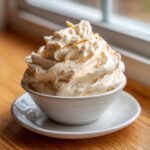A generous swirl of fluffy cinnamon butter, dusted with spice, served in a small white bowl.