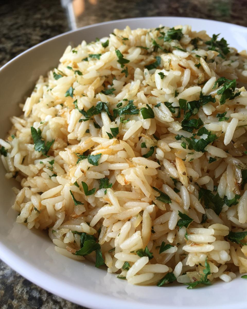 Close-up of a white bowl filled with fluffy, golden rice pilaf garnished generously with chopped fresh parsley.