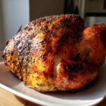 A perfectly roasted, golden-brown turkey seasoned with garlic and herbs, resting on a white platter.