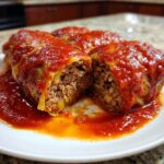 Close-up of delicious cabbage rolls cut open, showing the savory meat and rice filling, smothered in rich tomato sauce.