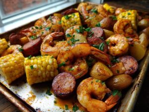 Close-up of a flavorful sheet pan shrimp boil featuring seasoned shrimp, smoked sausage, corn on the cob, and potatoes.