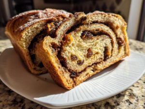 Close-up of two thick slices of homemade raisin bread showing the interior cinnamon swirl and plump raisins.
