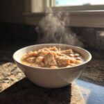 A steaming white bowl filled with hearty crockpot white chicken chili, featuring shredded chicken and white beans.