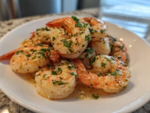 Close-up of cooked air fryer frozen shrimp seasoned with garlic and fresh parsley on a white plate.