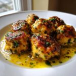 Close-up of several golden-brown chicken piccata meatballs served in a bright lemon butter sauce and garnished with parsley.