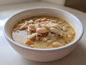 Close-up of a bowl of creamy white chicken chili featuring shredded white chicken and white beans.