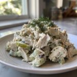 A generous serving of creamy dill pickle chicken salad mixed with chopped pickles and topped with fresh dill.