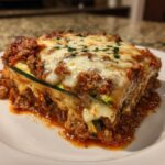 A close-up, appetizing slice of zucchini lasagna layered with meat sauce and topped with bubbly melted mozzarella cheese.