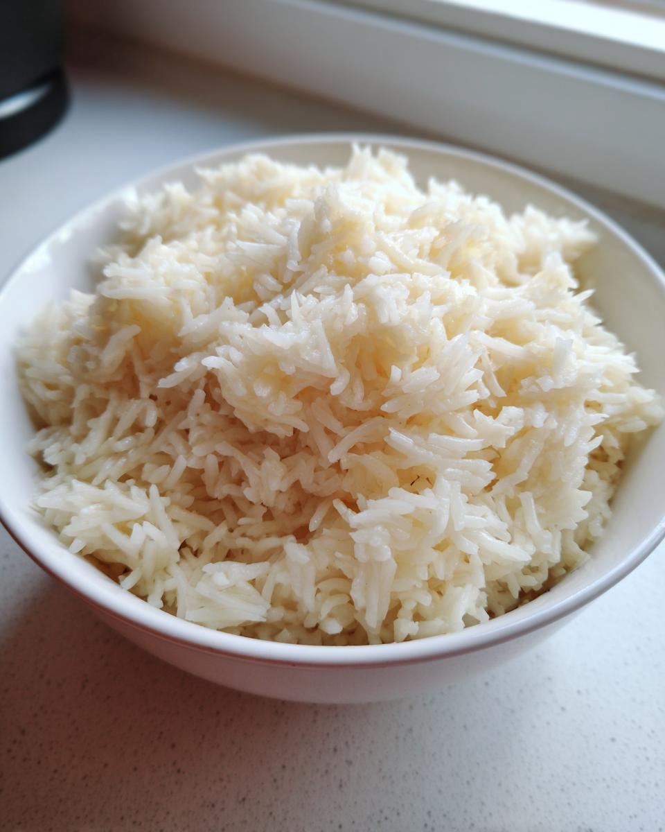 Close-up of fluffy white rice served in a small white bowl, ready for making cheesy rice.