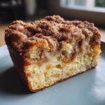 Close-up of a thick slice of french toast casserole with a rich, crumbly cinnamon streusel topping.