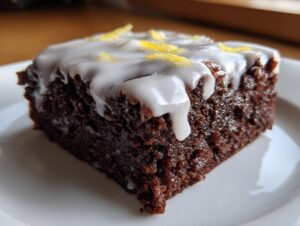 Close-up of a fudgy, dark chocolate Lemon Brownies slice topped with white glaze and lemon zest.