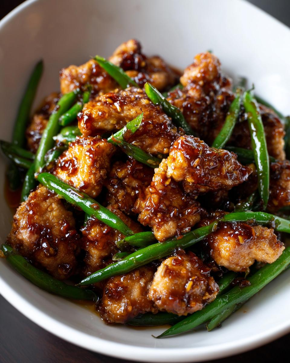 Close-up of crispy, glazed chicken pieces mixed with bright green beans, a perfect example of chicken and green beans.