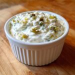 Close-up of creamy homemade tartar sauce with visible relish and capers in a small white bowl.
