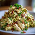 Close-up of creamy honey mustard chicken salad mixed with bacon crumbles and fresh parsley.