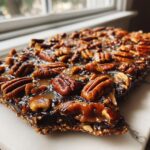 A close-up view of a rich, dark Pecan Pie Bark topped generously with glossy caramel and whole pecans.