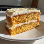 Close-up of a thick slice of Creamsicle Cake with two layers of orange-hued cake and white frosting.