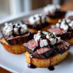 Close-up of perfectly cooked steak crostini topped with creamy cheese and balsamic glaze.