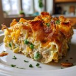 A hearty slice of tuna noodle casserole with a crispy, golden-brown topping served on a white plate.