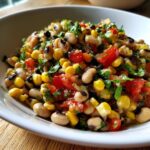 Close-up of a vibrant cowboy caviar recipe featuring black-eyed peas, corn, diced tomatoes, and fresh cilantro.