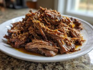 A close-up of fork-tender, shredded Mississippi pot roast piled high on a white plate with savory juices.